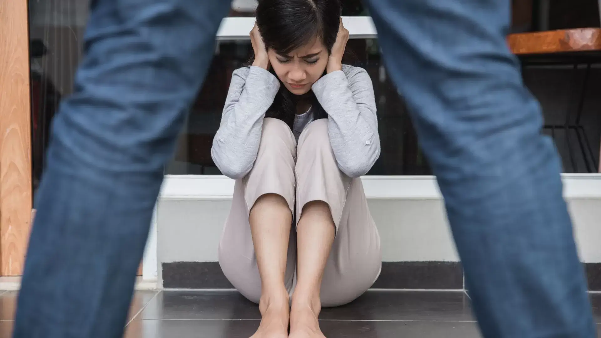 Young woman covering her ears while her partner shouts, symbolizing the emotional strain and trauma addressed through Family Counselling Therapy for Abuse at Oakville Family Counselling Therapy.